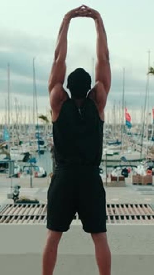 Vertical video, Muscular Man Stretching By The Marina