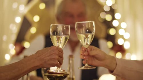 Família extensa sentada à mesa dentro de casa no Natal, tilintando copos com