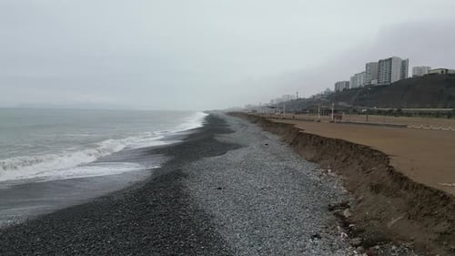 Aerial dolly shot of the beach landscape in miraflores lima in peru with black gravel and a view of