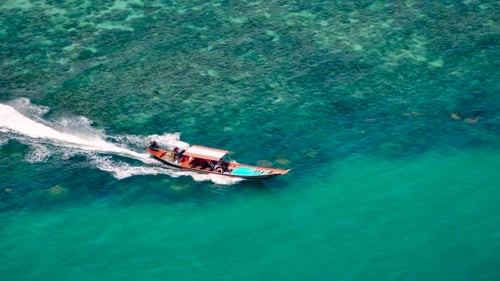 Drone shot of a small boat sailing next to the island.