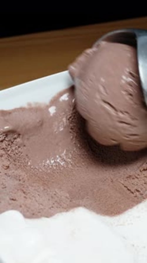 Vertical video. I shape a scoop of chocolate ice cream using a special spoon, close-up.