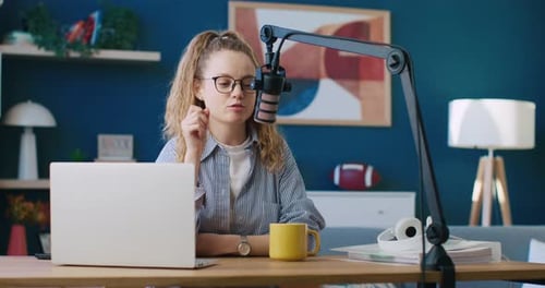 Woman Speaking Into Microphone at Desk with Laptop