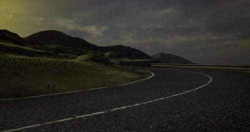 Curved Mountain Road Winding Through Lush Green Hills at Twilight