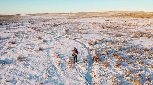 Aerial View of a Lonely Human Walking Through Snowy Desert