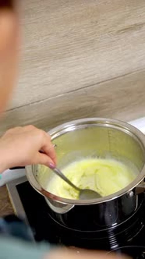 Butter, die in einem Topf auf einem Herd schmilzt und von einer Frau gerührt wird