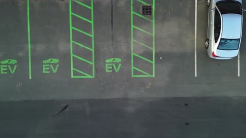 Aerial view of green-marked EV charging parking spaces for electric cars outdoors