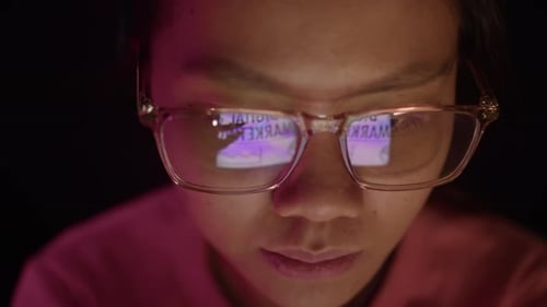 Person looking at screen, glasses reflect light