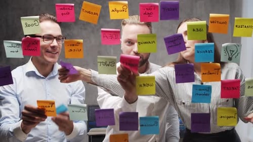 Team of Business People is Doing Brainstorm at a Meeting Using Stickers on the Glass Office Workers
