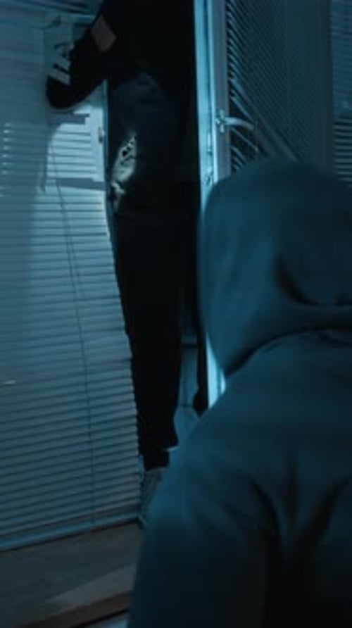 Vertical of Two Intruders with Torches Sneaking into Office through Window