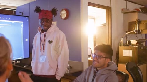 Des hackers souriants discutent lors d'un hackathon dans un bureau ensoleillé (20-24 ans)
