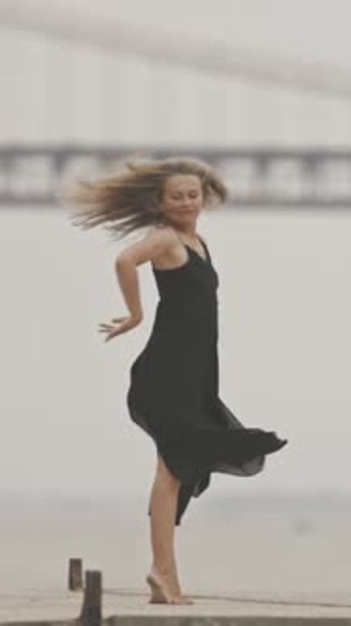 Graceful Woman Dancing Barefoot in Dress by the Water