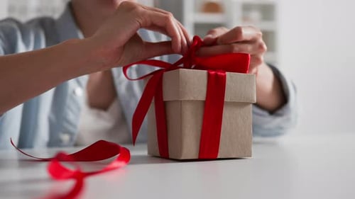 Close-up female hands tying a bow on a gift cooking gift box packaging gift to loved one Festive day