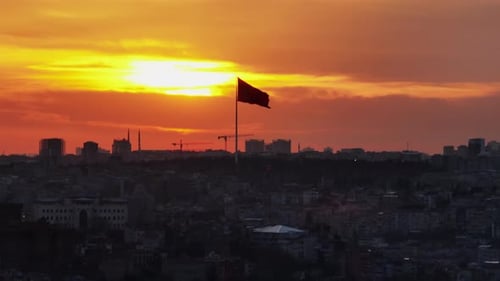 Cityscape Silhouette with Flag at Sunset