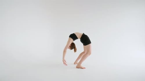 Mujer joven realizando la postura de la rueda del antebrazo en un estudio minimalista