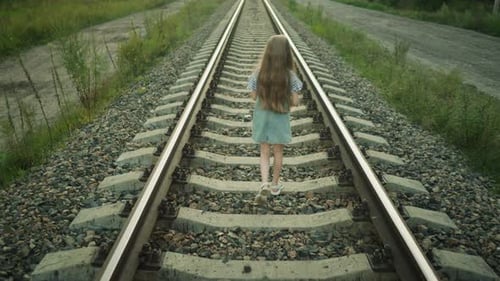 Girl Walks on Railway Tracks in Rural Landscape