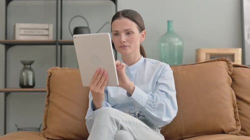 Woman with Tablet Looking Upset on Couch Indoors