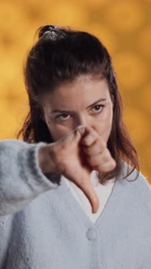 Vertical Video Disappointed Woman Bashing Book Showing Thumbs Down Sign Studio Background