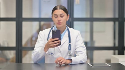 Mixed Race Female Doctor Using Smartphone in Hospital