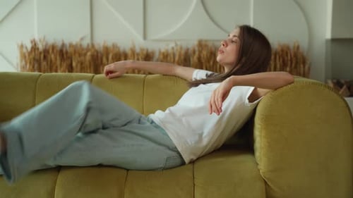 Tired Young Woman Falls on the Sofa in the Living Room of the House