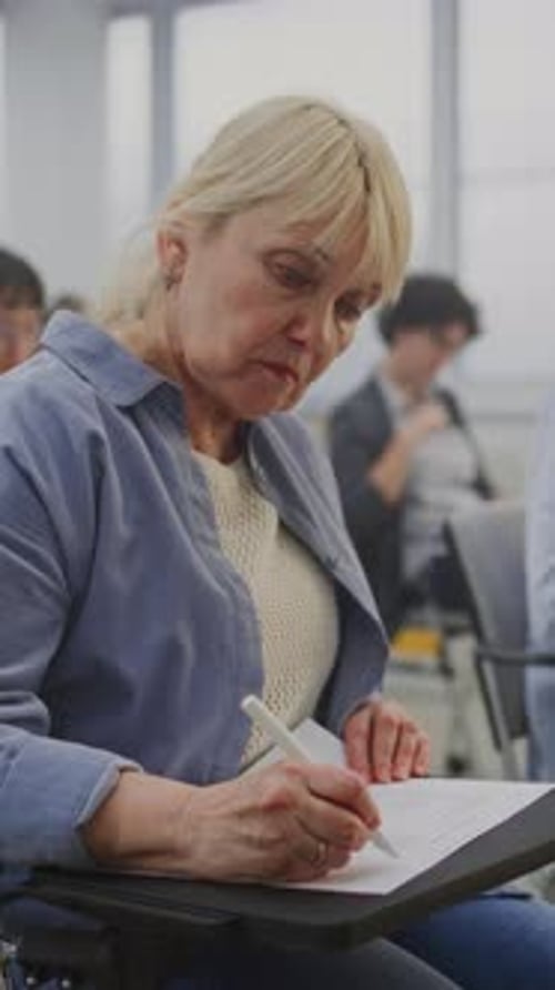 Group Mature Students Works on Written Exercises As Teacher Explains Material