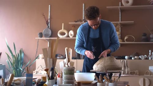 A Young Potter Guy Creates a Sculpture in a Bright Workshop with His Hands The Male is in a Creative