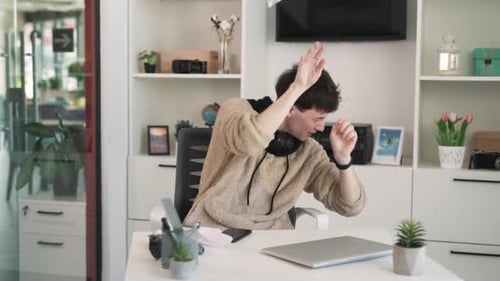 Der Teenager sitzt mit einem Laptop an einem Schreibtisch, und Papierbälle werden auf ihn geworfen. Der Junge