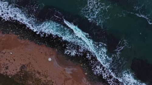 Waves crash on rocky shore at coastal area during daylight hours