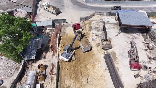 Excavatrice chargeant de la terre dans un camion à benne basculante sur un chantier de construction
