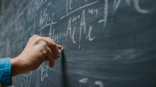 Hand Holding Chalk and Writing Complex and Sophisticated Mathematical Formula/ Equation on the Blac