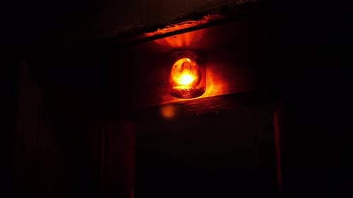 Closeup of a Rotating Red Emergency Siren Lamp on the Wall of a Dark Tunnel