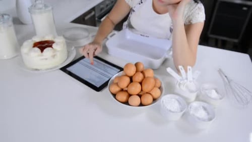 Woman uses tablet baking in bright, modern kitchen