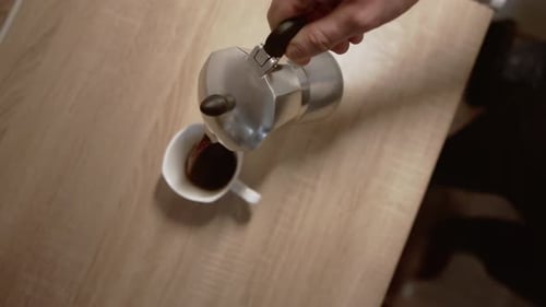 Pouring Coffee from Moka Pot Into Cup