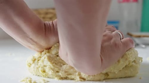 Hands Kneading Ball of Dough in Kitchen