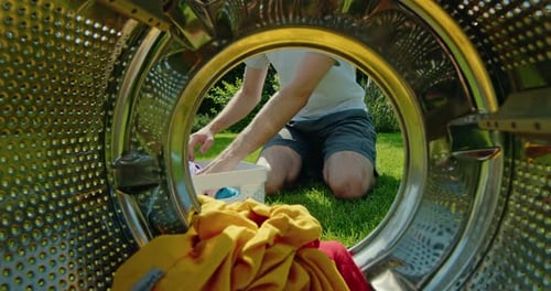 Man Putting Dirty Clothes Into the Washing Machine View From Inside the Machine