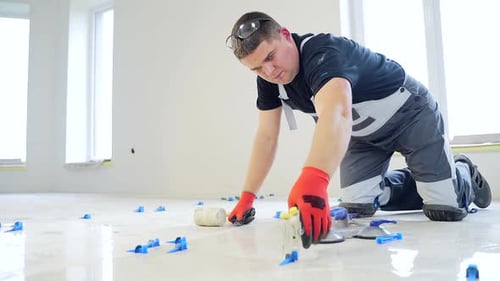 industrial tiler Professional builder worker installing floor a large ceramic tile at repair renovat
