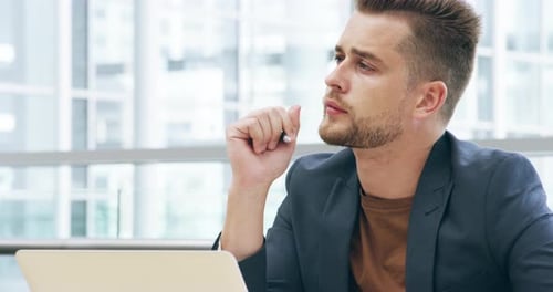 4k video footage of a handsome young man looking thoughtful while working in his office