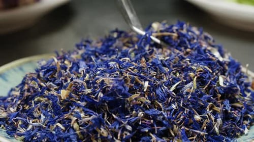 Tongs Picking Blue Dried Flower Petals From Plate