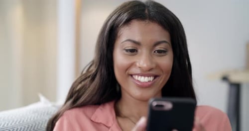 Woman Smiling While Using Her Phone at Home