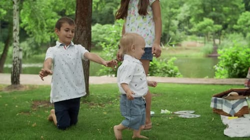Siblings Playing In Park. Young Family Having Picnic In Park. Smiling Children With Parents Spend...