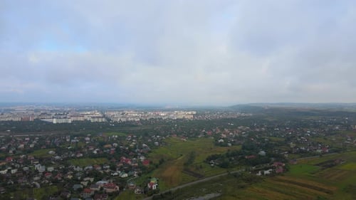 Aerial View From High Altitude of Distant City Covered with Puffy Cumulus Clouds Forming Before