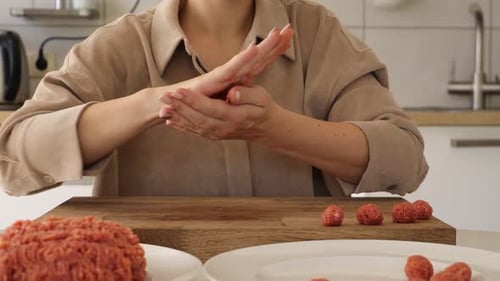 Close-up view of a woman skillfully preparing meatballs in a modern kitchen.