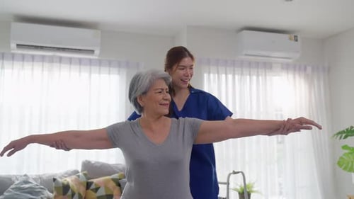 Senior Woman Doing Arm Stretches With Caregiver