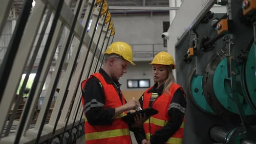 Factory Workers Inspect Industrial Equipment in Manufacturing Facility