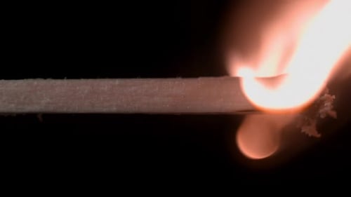 Horizontal Burning Match Against A Dark Background