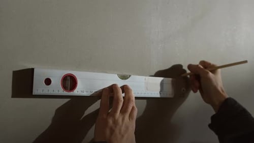 Construction Worker Marking Measurements on Concrete Wall at Building Site