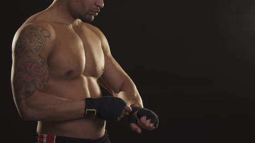 Muscular Boxer Wraps Hands in Preparation