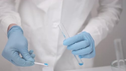 Adding blue substance to test tube, lab work