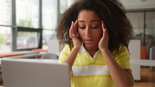 Stressed Woman Rubbing Eyes While Working at Desk