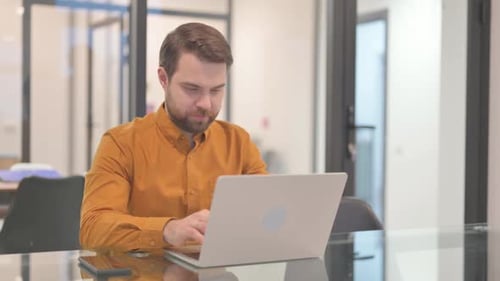 Young Man Working on Laptop in Office