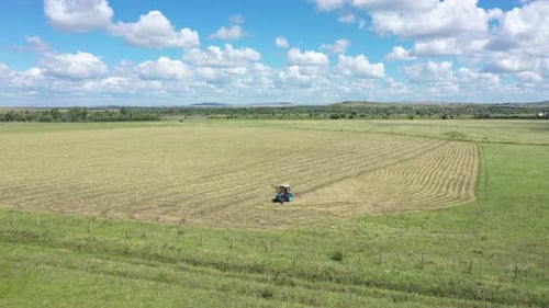 Aerial View of Agriculture Tractor Collecting Dry Hay in the Field